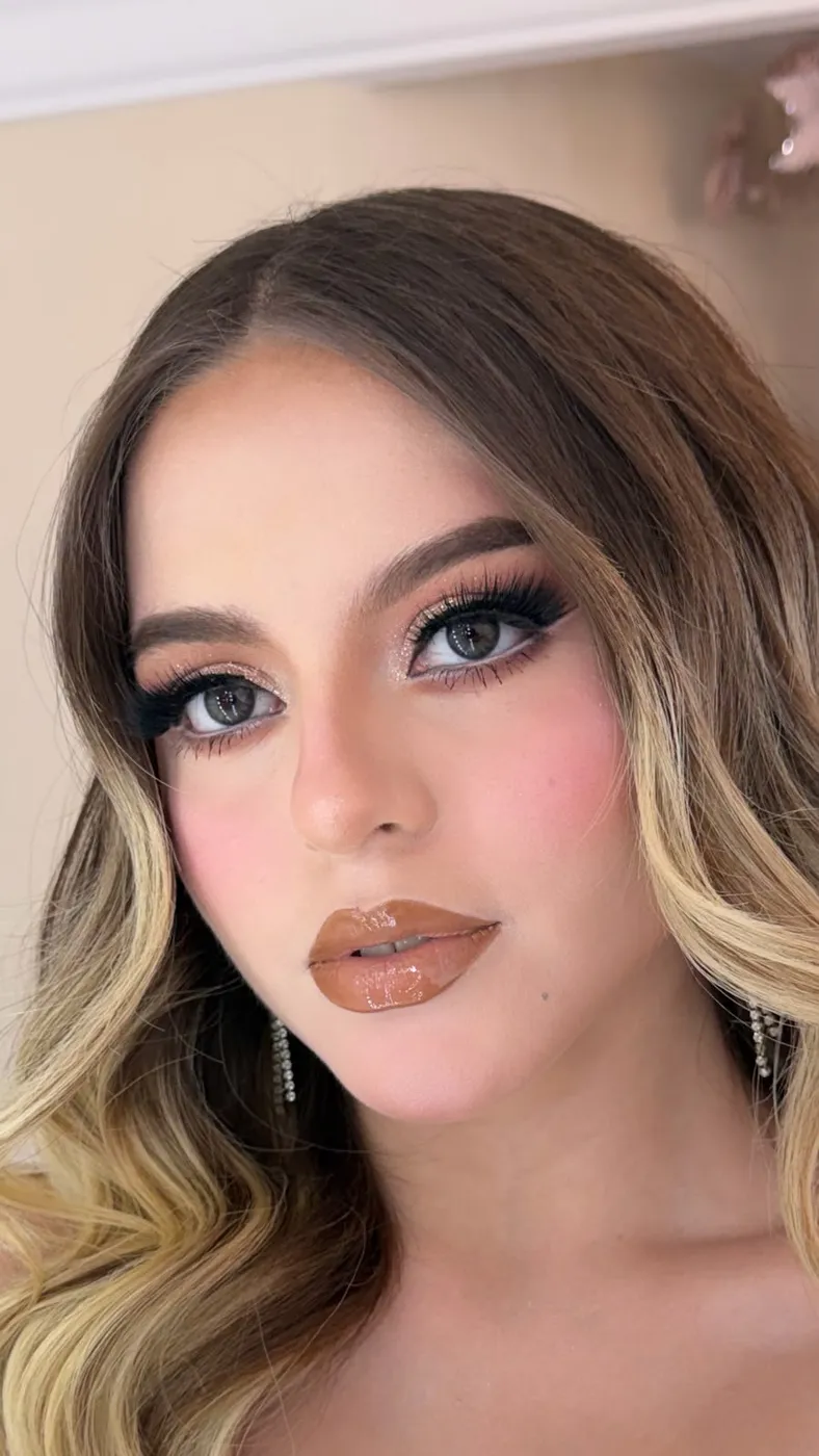 Primer plano de maquillaje glam con sombra champagne y labios café gloss